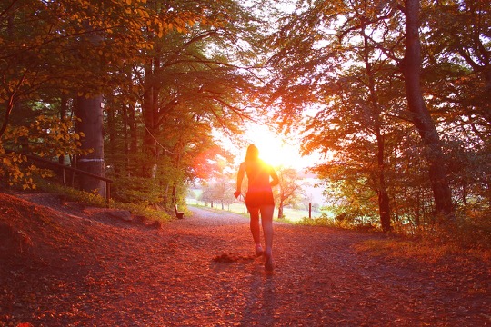 Photo of woman running into morning sun